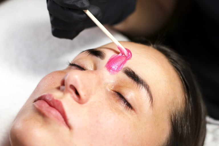 Close-up of a beauty professional applying wax to eyebrows